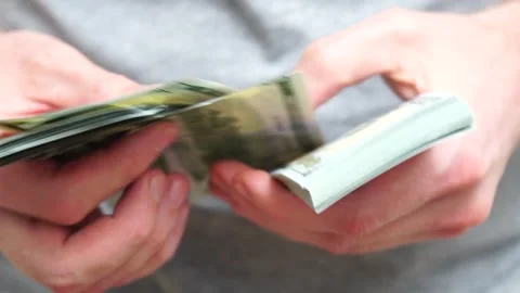 Male hands counting a stack of hundred-dollar US banknotes. Concept of Stock Footage 245540756