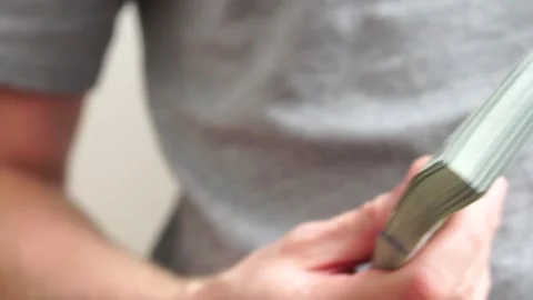 Male hands counting a stack of hundred-dollar US banknotes. Concept of Stock Footage 245973701