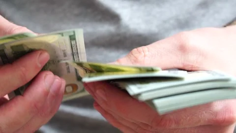 Male hands counting a stack of hundred-dollar US banknotes. Concept of Stock Footage 246958365