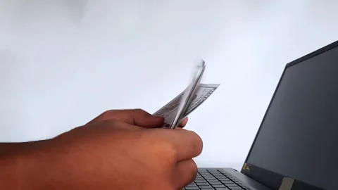 Male hands counting US dollar banknotes at the table in front a laptop computer Stock Footage 294184979