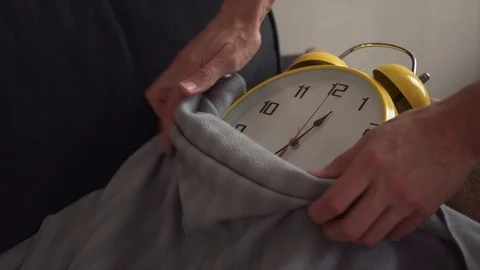 Male hands covers the clock lying on the sofa with a blanket Stock Footage 80814912