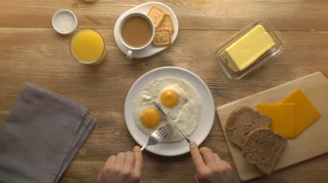Male hands cut the fried eggs on white plate, top view Stock Footage 67533982