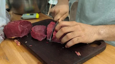 Male hands cutting raw beef into smaller pieces on cutting board before 库存影片 340200386