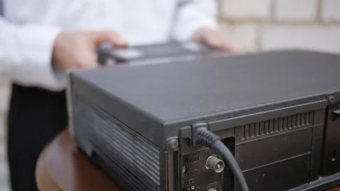 Male hands eject the tape from video cassette recorder and puts it on the VCR. Stock Footage 69798317