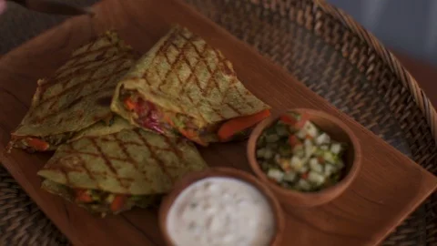 Male hands with fork and knife cut Vegetable quesadils on a wooden round board Stock Footage 101637066