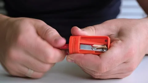 Male hands hold the sharpener and sharp the wooden pencil. The sharpening of Stock Footage 321861883