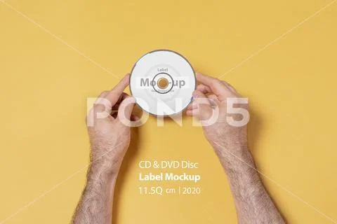 Male hands holding a CD-DVD in front of yellow background mock-up series PSD Template