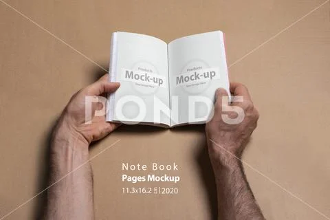 Male hands holding an opened note book-catalog with blank pages on brown back PSD Template