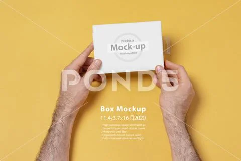 Male hands holding a small box in front of yellow background mock-up series PSD Template