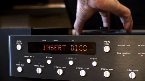 Male hands inserting CD disk in music player. Close up black digital player Vidéo 129210738