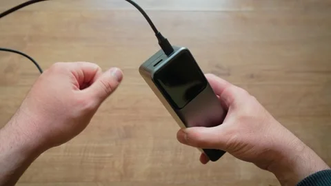 Male hands inserting USB cable into power bank portable charger close up modern Stock Footage 335816819