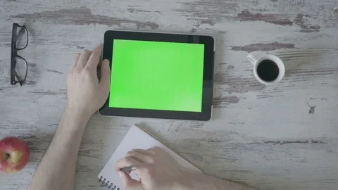 Male hands make notes in a notebook, next is a tablet with a green screen Stock Footage 80533688