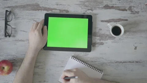 Male hands make notes in a notebook, next is a tablet with a green screen Stock Footage 80533837