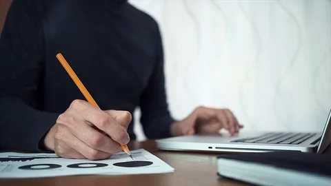 Male hands making note with pencil at printed analyzing graphs Stock Footage 79901574