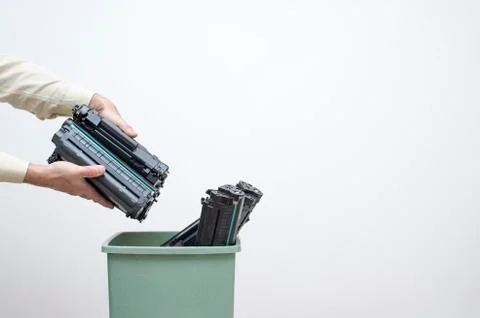 Male hands of an office worker stack spent cartridges in a bucket against a w Stock Photos