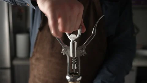 Male hands opening bottle of white wine with metal corkscrew at home kitchen Stock Footage 220570976