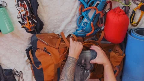 Male hands packing climbing backpack top view on gear layout, organizing Stock Footage 333765918