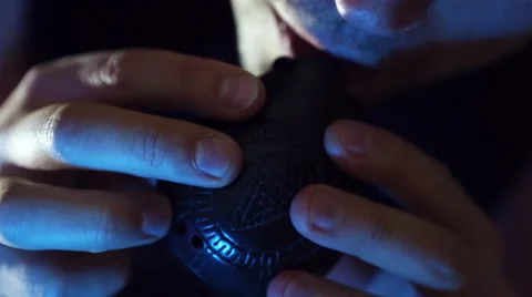 Male hands playing okarina (wind-flute), incense on a dark background. Stock Footage 59643280