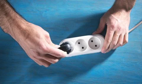 Male hands plug electrical plug in extension block. Stock Photos