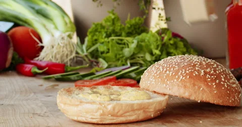 Male hands preparing ingredients making fresh vegan burger on toasted bun, Stock Footage 237973532