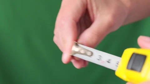 Male hands pull the measuring tape out of tape measure, close up. Vídeo Stock 253971231