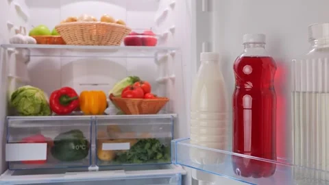 Male hands put a bottle of cherry juice in the fridge with vegetables Stock Footage 260770018