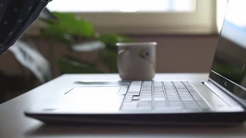 Male hands put a cup on the table, typing on a laptop Stock Footage 244599125