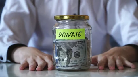 Male hands put on table saving money In glass jar filled with dollars banknotes Video stock 317049048