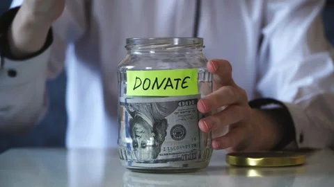 Male hands put on table saving money In glass Jar filled with Dollars banknotes. Stock Footage 317049058