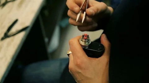 Male hands regulate electronic cigarette coils. Stock Footage 72933104