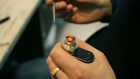 Male hands regulate electronic cigarette coils. Vídeos de archivo 72933106