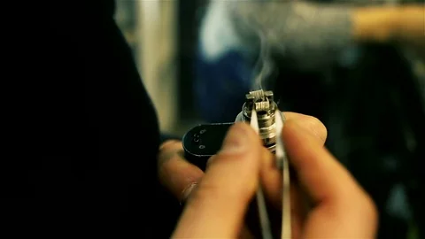 Male hands regulate electronic cigarette coils. Stock Footage 72933111