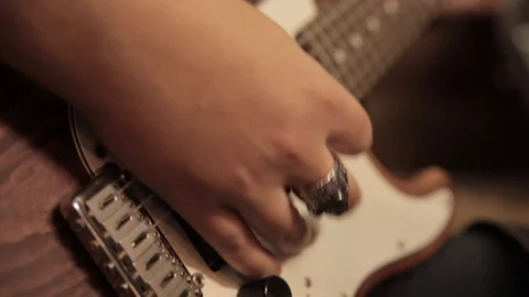 Male hands with a ring playing a brown and white electric guitar Stock Footage 98290077