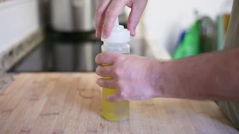 Male hands screwing cap on squeeze bottle of olive oil Stock Footage 335834330