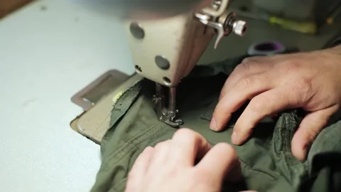 Male hands sewing on sewing machine the fabric of a military uniform is green Stock Footage 201431767
