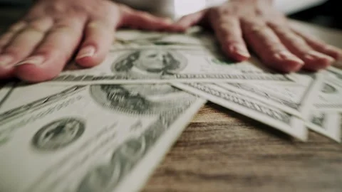 Male hands sliding stack of 100 dollar bills across wooden table. Video stock 306622687