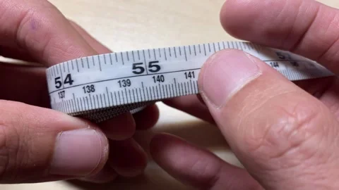 Male hands slowly pull measurement tape roll on wooden table close up shot Stock Footage 248205627