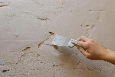 Male hands with spatula using putty for wall, builder making overhaul. Stock Photos