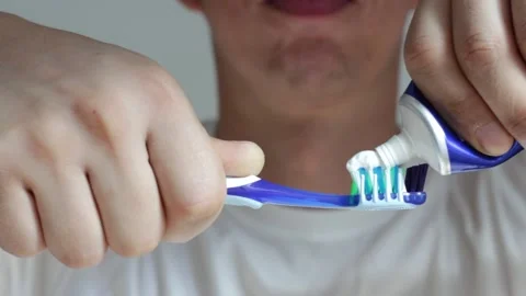 A male hands squeeze toothpaste onto a toothbrush close-up. Stock Footage 163252471