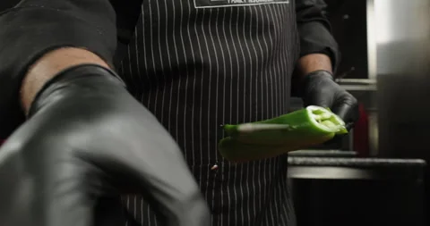 Male hands string green spicy pepper on a skewer. Chef prepares vegetables in a Stock Footage 262875136