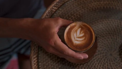 Male hands take patterned coffee. Man drinking cappuccino in cafe Stock Footage 101634418