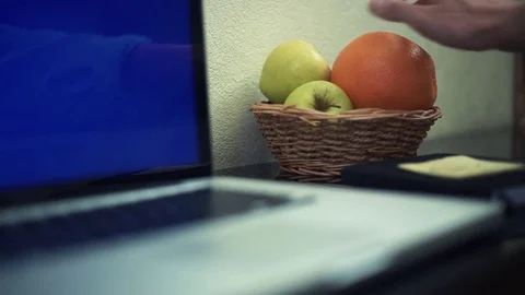 Male hands taking orange using laptop with green screen at home. Stock Footage 82934148
