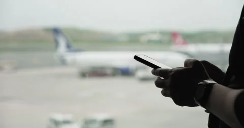 Male hands using app on smartphone, waiting for a flight, texting message Stock Footage 293474712