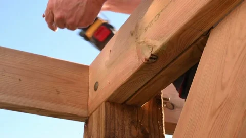 Male hands using impact driver to build wooden gazebo Stock Footage 139991170