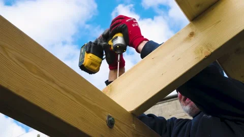 Male hands using impact driver to build wooden roof on gazebo. diy home project Stock Footage 149944907