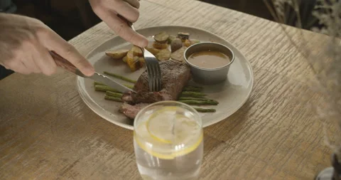 Male hands using knife and fork while cutting beef steak on grill Stock Footage 103675492