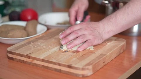 Male hands using a large knife to gather diced boiled potatoes from a wooden Stock Footage 320822909