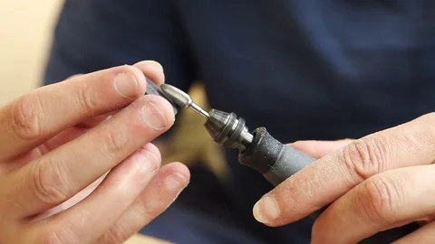 Male hands using rotary tool flexible shaft to carve out a guitar pick from horn Stock Footage 114138526
