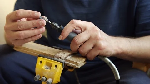 Male hands using rotary tool flexible shaft to carve out a guitar pick from horn Stock Footage 114138566