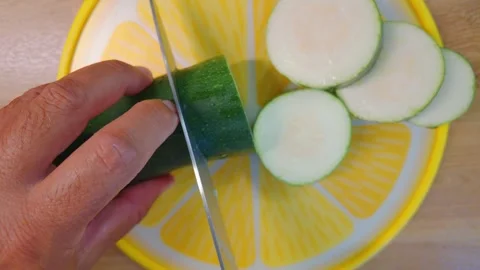 Male hands using a sharp steel knife to carefully chop a fresh green zucchini Stock Footage 342076501